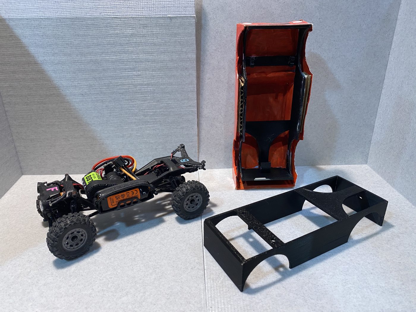 Chassis, a paper body turned upside down with the shell fitted inside it, and a bare shell alongside.
